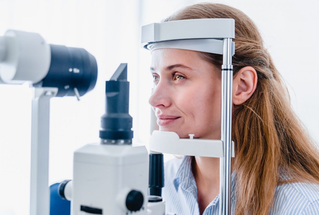 Young woman patient undergoing ophthalmic vision check up : side view